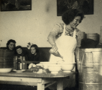 811776 Afbeelding van een medewerkster van een Centrale Keuken (gaarkeuken) die helpt bij het uitdelen van voedsel in ...